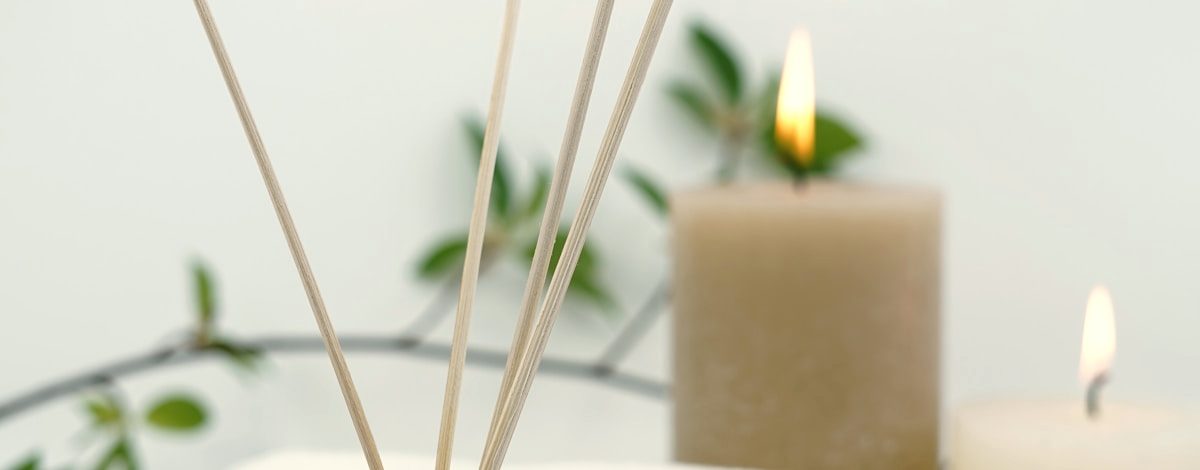 Candles and reed diffuser sticks against a light wall